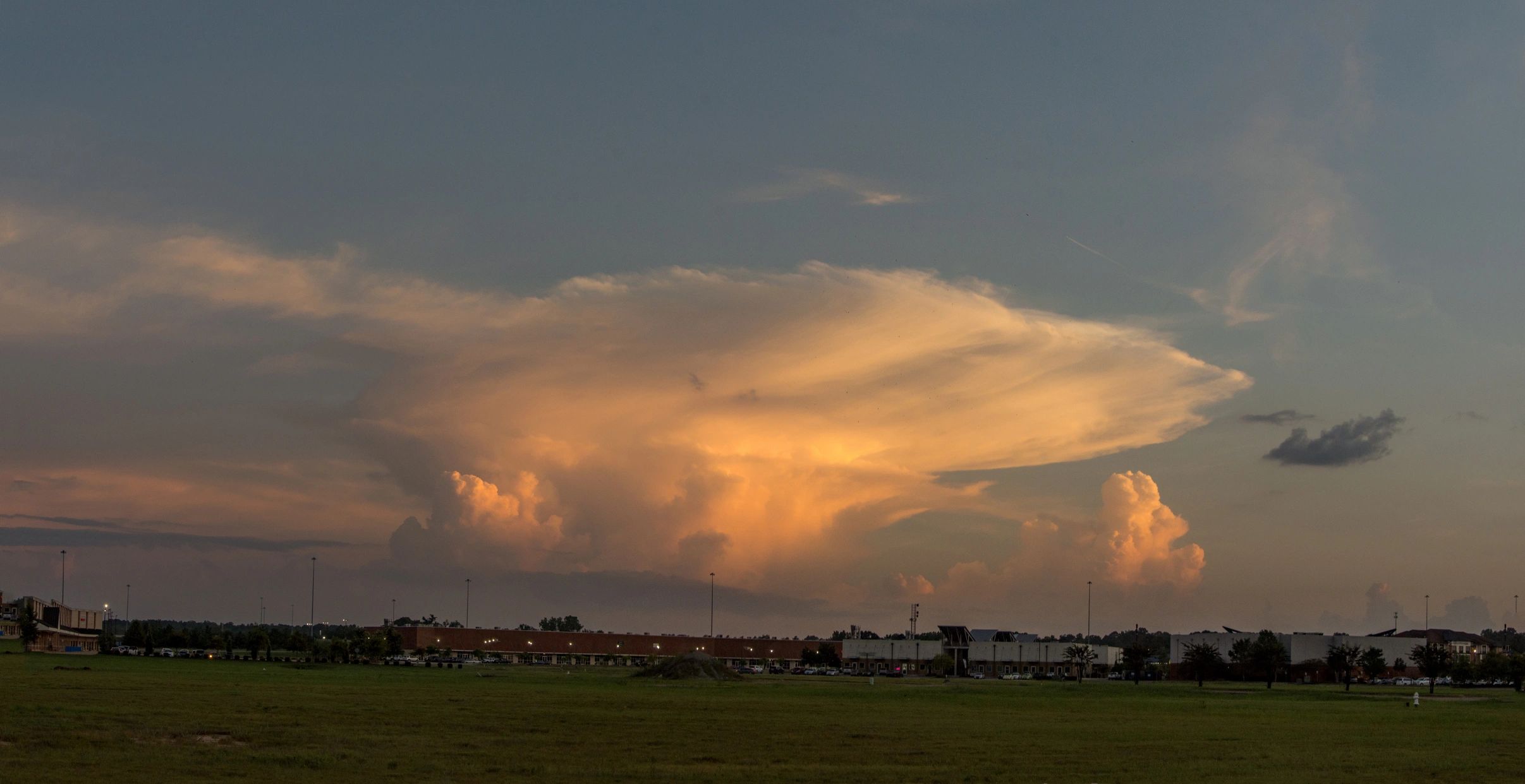 Panoramic thunderstorm cloud formation over open landscape