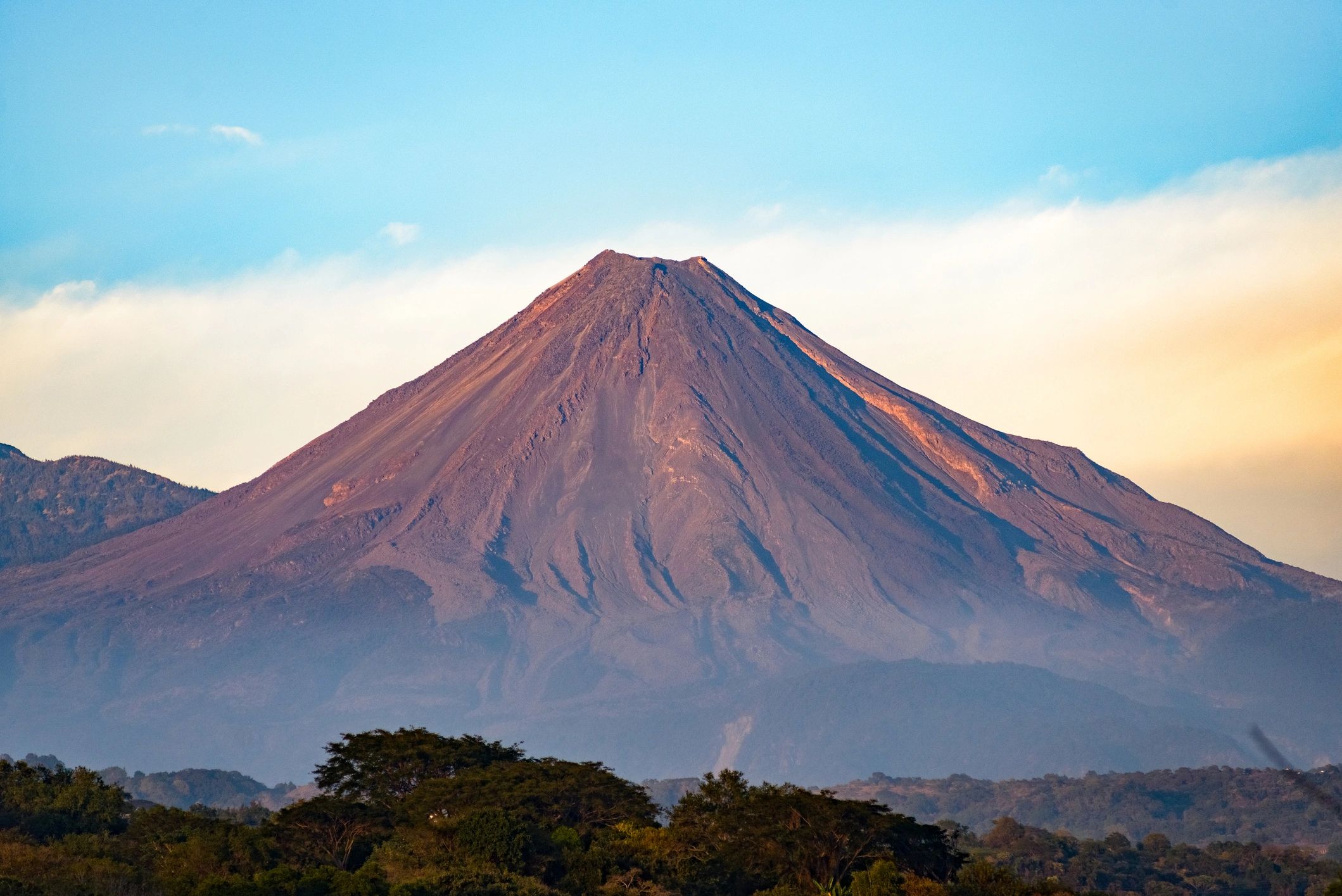Volcano rising above landscape under clear sky