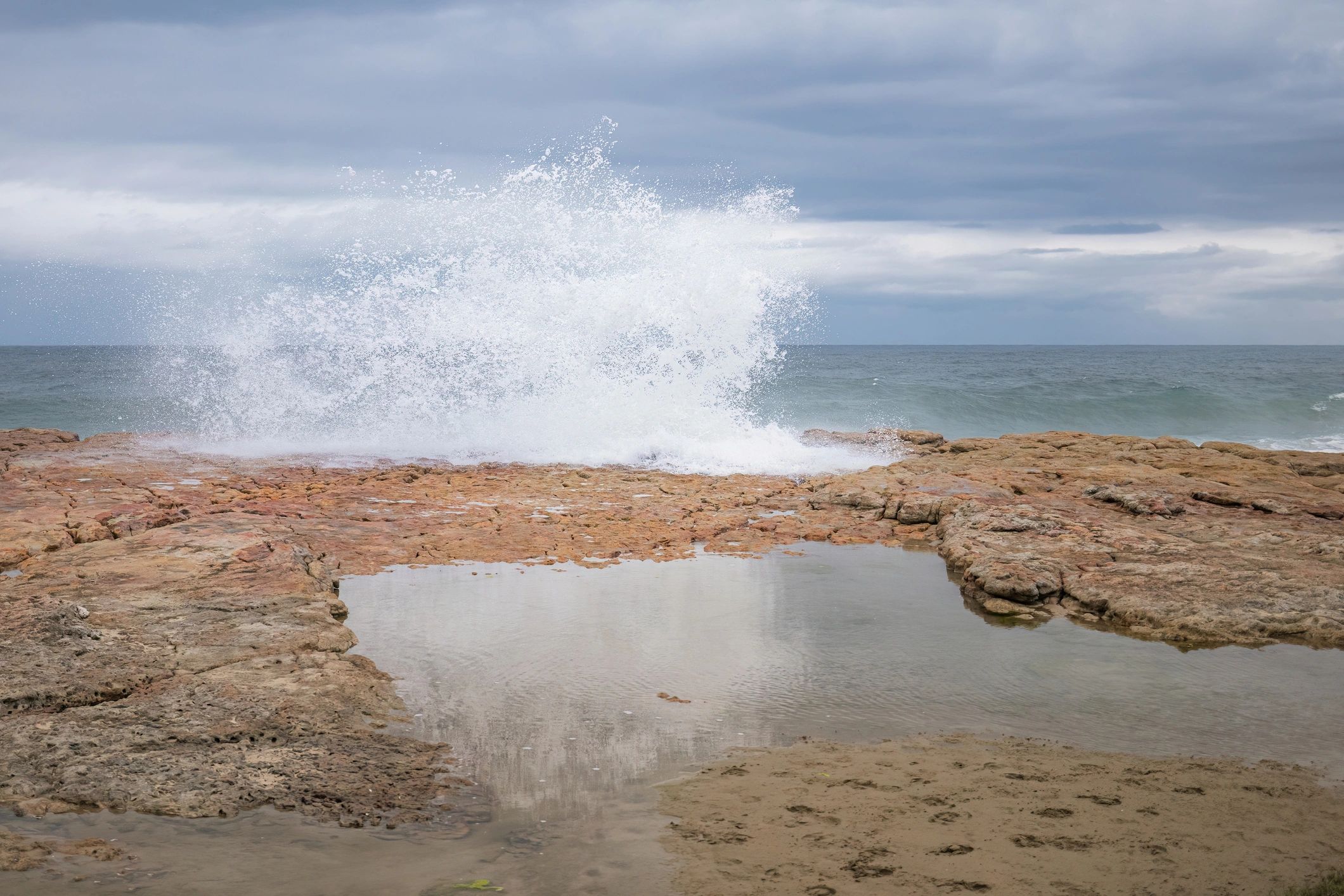 Powerful ocean wave crashing against rocky shoreline