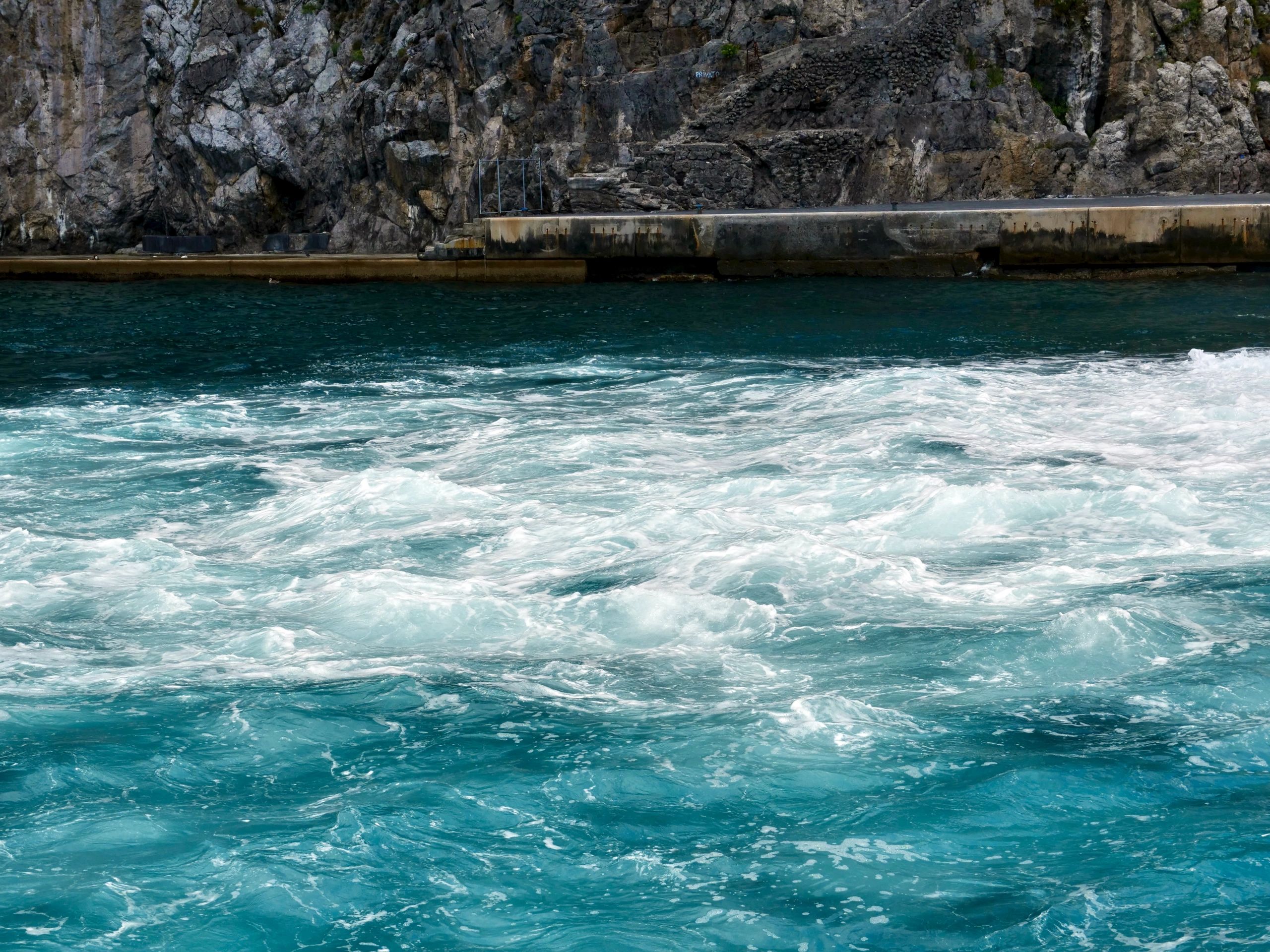 Foamy seawater swirling near rocky shore